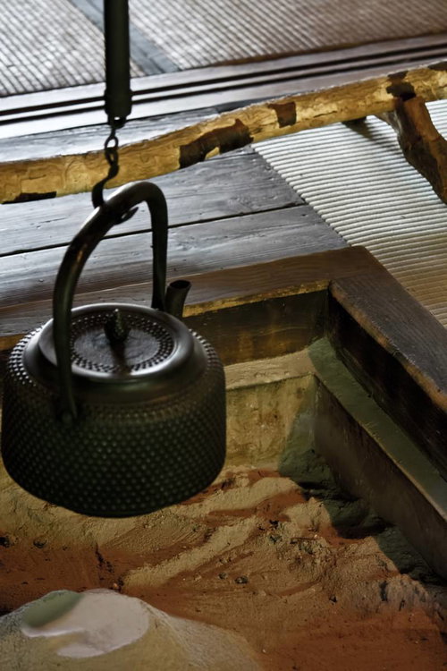 古い梁の下に鎖で吊るされた囲炉裏の黒い鉄瓶