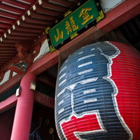 朱色の柱に囲まれた浅草の雷門の大きな赤い提灯の写真
