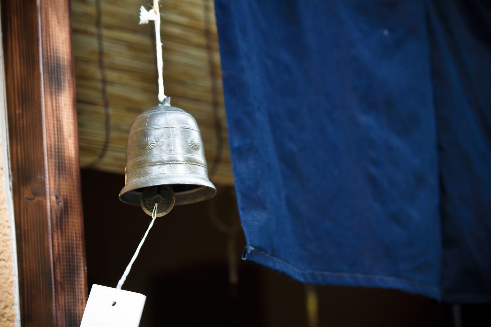 白い紐で吊り下がる金属の鐘型の風鈴と短冊