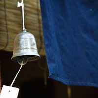 白い紐で吊り下がる金属の鐘型の風鈴と短冊の写真