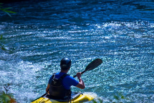夏の渓流でカヌーを漕ぐ男性と急流