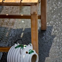 木のベンチの下に置いた豚型の蚊取り器とうちわの写真