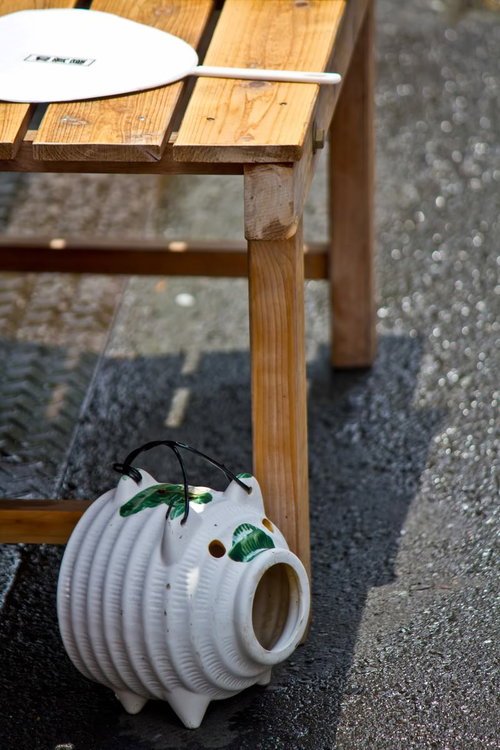 木のベンチの下に置いた豚型の蚊取り器とうちわ