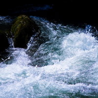 白い泡と苔の岩が映る渓流の激しい水しぶきの写真