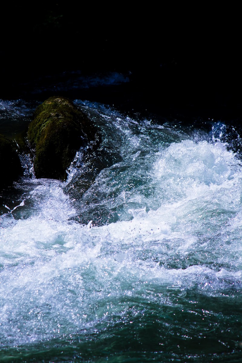 白い泡と苔の岩が映る渓流の激しい水しぶき