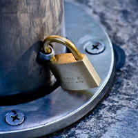 木の柱に取り付けた金属の留め具と金色の南京錠の写真