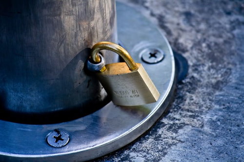 木の柱に取り付けた金属の留め具と金色の南京錠