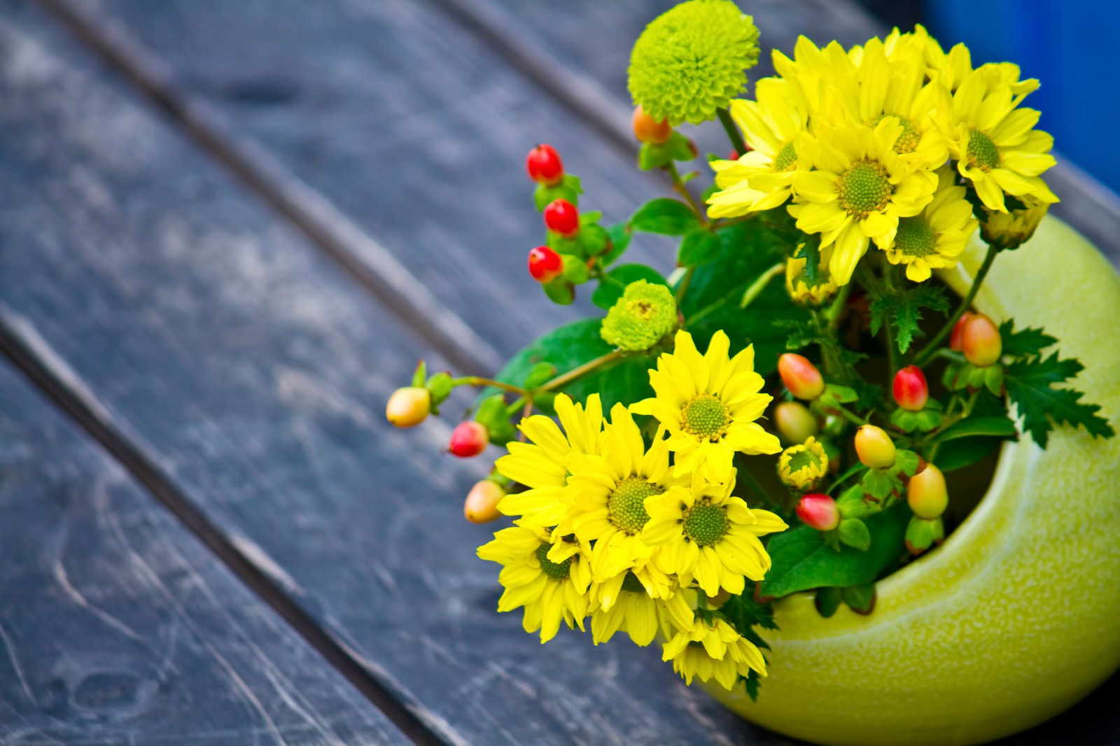 青灰色の板の上に置いた黄色い花の花瓶