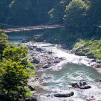 大きな岩がある御岳渓流の谷間と吊り橋の写真