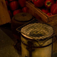 リンゴと並ぶ昔懐かしい七輪と薄切り食材の網焼きの写真