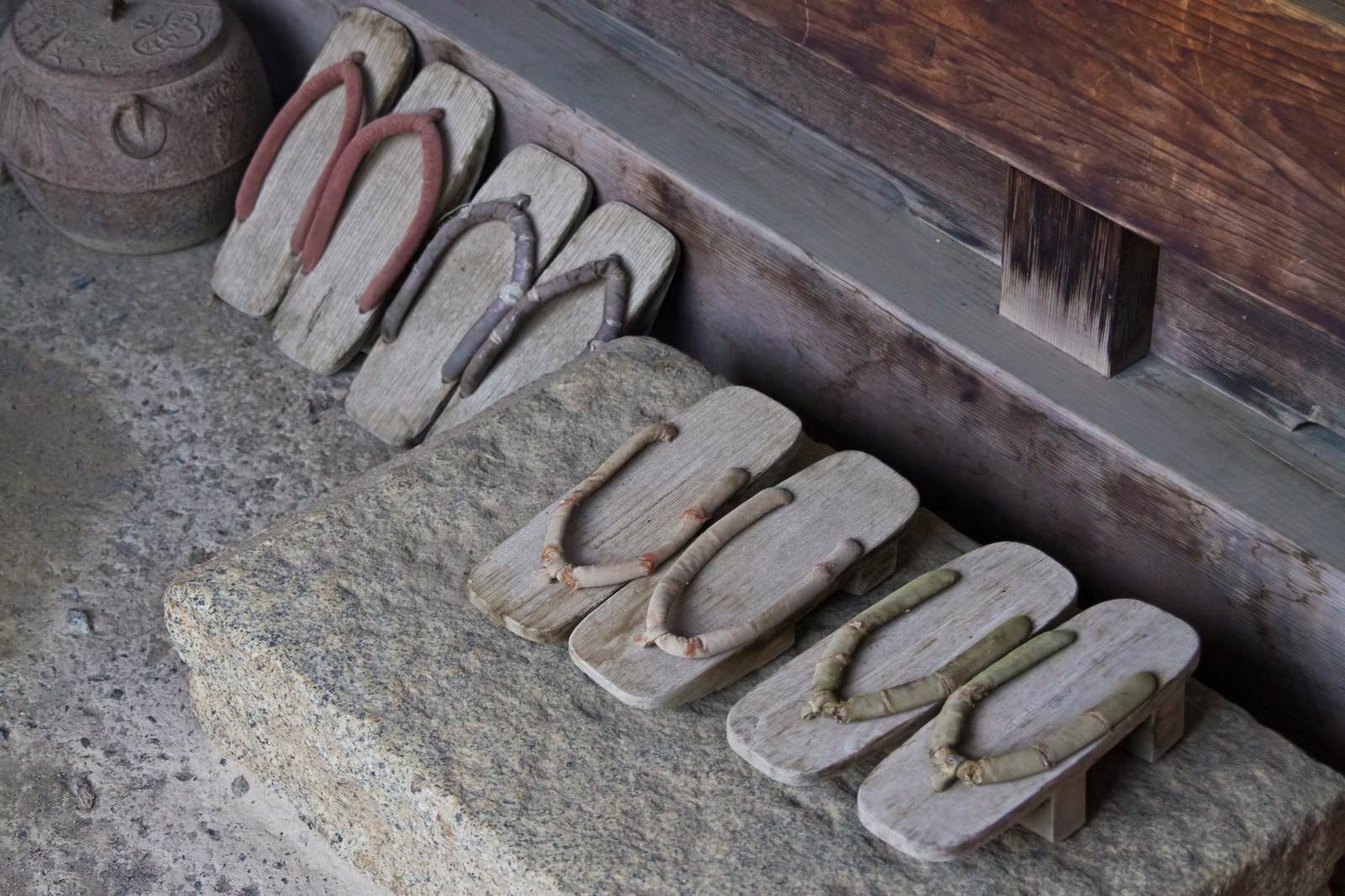 石の台に色とりどりの鼻緒の下駄が7足並ぶ