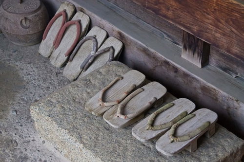 石の台に色とりどりの鼻緒の下駄が7足並ぶ