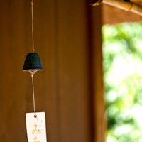 窓辺の光に照らされた緑の鐘型の軒先の風鈴の写真