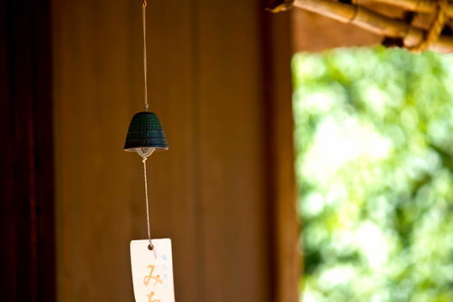 窓辺の光に照らされた緑の鐘型の軒先の風鈴