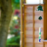 木の格子戸の前に吊り下がる緑と青の庭先の風鈴の写真