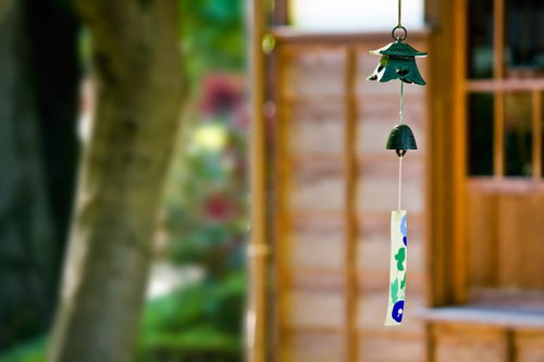 木の格子戸の前に吊り下がる緑と青の庭先の風鈴