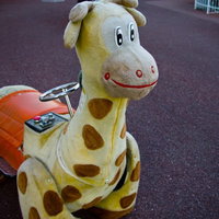 コイン投入口が付いた黄色いキリンのぬいぐるみ乗り物の写真