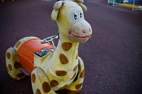 コイン投入口が付いた黄色いキリンのぬいぐるみ乗り物