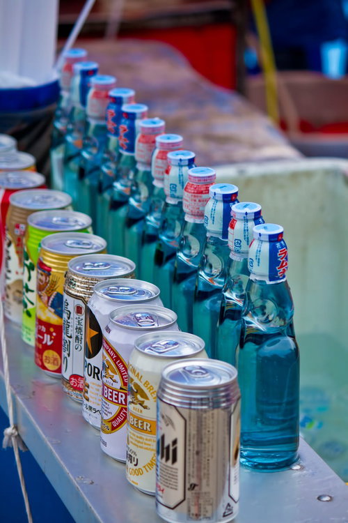 金属の台に並ぶ露店のラムネとお酒の瓶と缶
