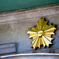 コンクリート壁に付いた金色の星形の交番桜のエンブレムの写真