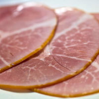 白い皿に並べたピンクのスライスハム3枚の写真