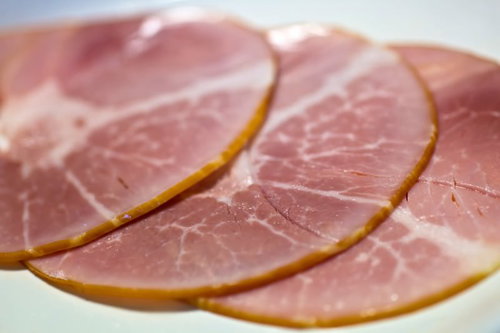 白い皿に並べたピンクのスライスハム3枚