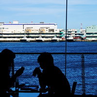 港が見える窓辺で向かい合う恋人のシルエットの写真