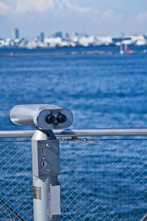 フェンス越しに青い海を見渡す観光望遠鏡