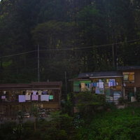 深い森の中腹に建つ明かりが灯る山の中の民家の写真