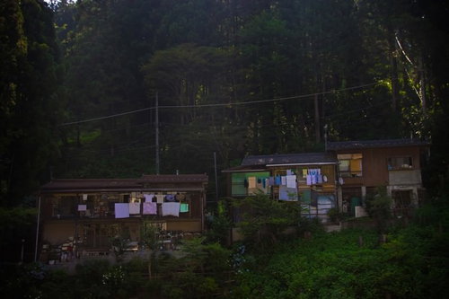 深い森の中腹に建つ明かりが灯る山の中の民家