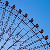 青空を背景に赤いゴンドラが並ぶ夕暮れの観覧車の写真