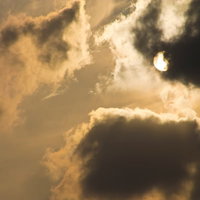 厚い雲の間から光が漏れる夕暮れの太陽と空の写真