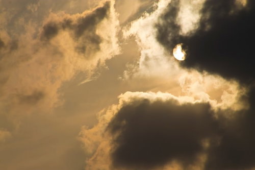 厚い雲の間から光が漏れる夕暮れの太陽と空