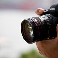 一眼レフを持つ姿とCanonズームレンズの写真
