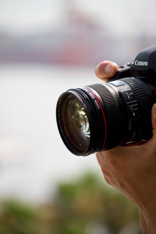 一眼レフを持つ姿とCanonズームレンズ
