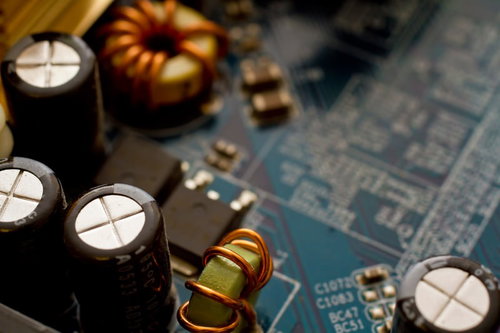 青い基板の上に並ぶコンデンサーやコイルのマザーボード部品