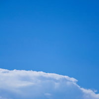 快晴の青空を背景に手すりに座る青年の写真