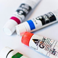 赤・青・ピンク・緑のキャップの絵具チューブが並ぶの写真