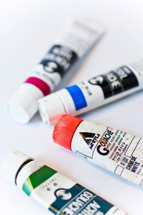 赤・青・ピンク・緑のキャップの絵具チューブが並ぶ