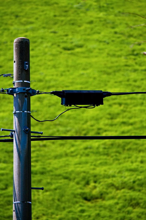 緑の草地を背景にした電柱の配線と金具