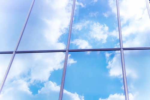 格子状のガラス窓に映り込む青空と白い雲