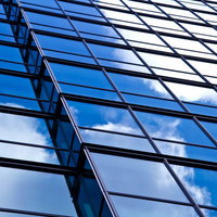 ガラス窓に映る青空と雲のビル外壁の写真