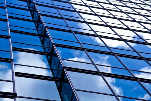 ガラス窓に映る青空と雲のビル外壁