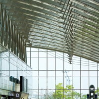 波打つ天井装飾が広がる人で溢れる空港ターミナルの写真