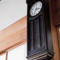 飾り彫りが施された古い木製の壁掛け振り子時計の写真