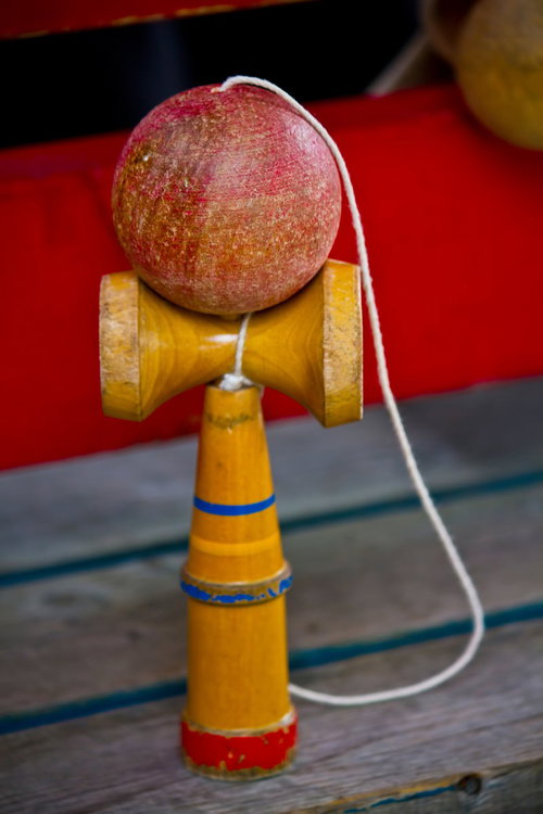 灰色の木目台に置いた使い古された赤い玉のけん玉