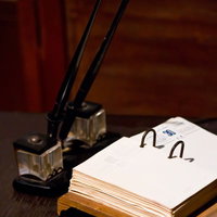 インク壺とペンが並ぶ古いデスクの白い紙のメモの写真