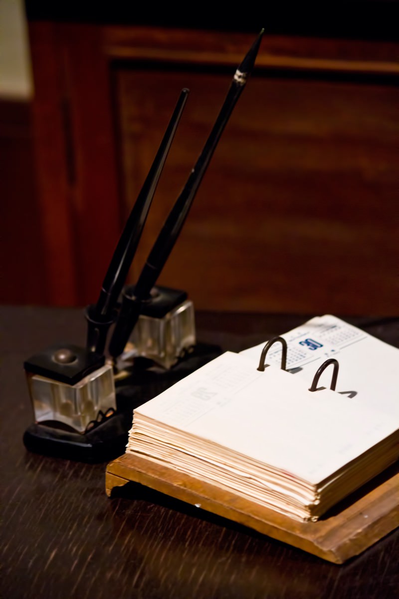 インク壺とペンが並ぶ古いデスクの白い紙のメモ