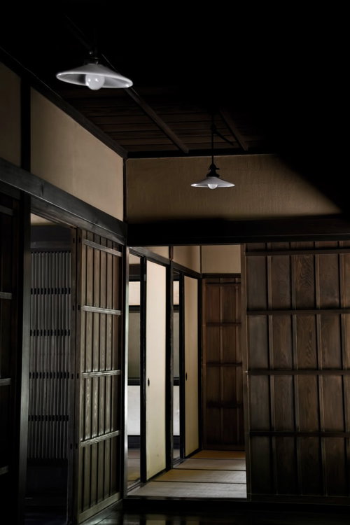 白い傘型照明が灯る古い木造建築の座敷の入口