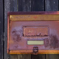 茶色とオレンジに錆びた古い壁付きの郵便受けの写真